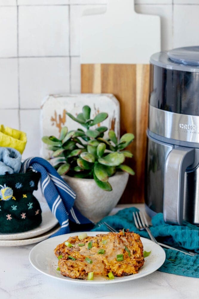 A plate of air fried chicken fried steak next to a food processor.