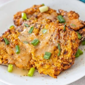 picture of air fried chicken fried steak on a plate topped with gravy and green onions
