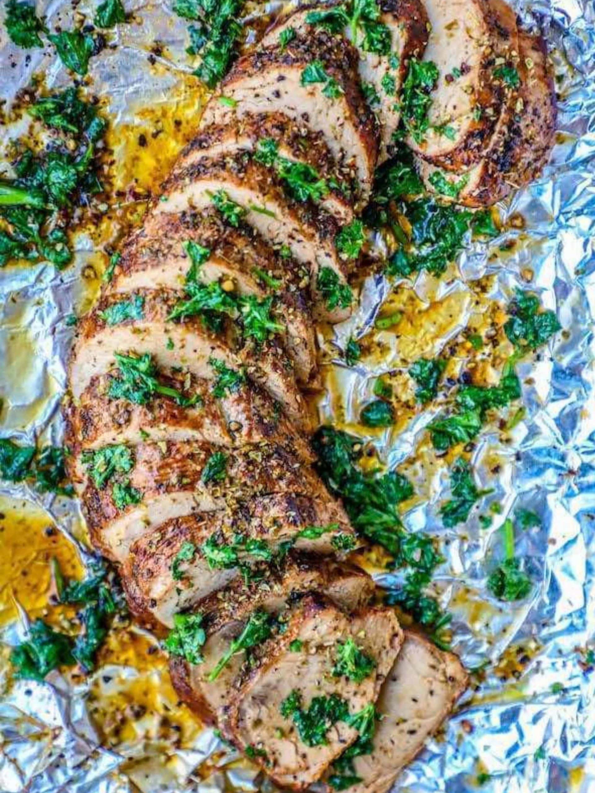 A deliciously baked pork tenderloin on a foil sheet.