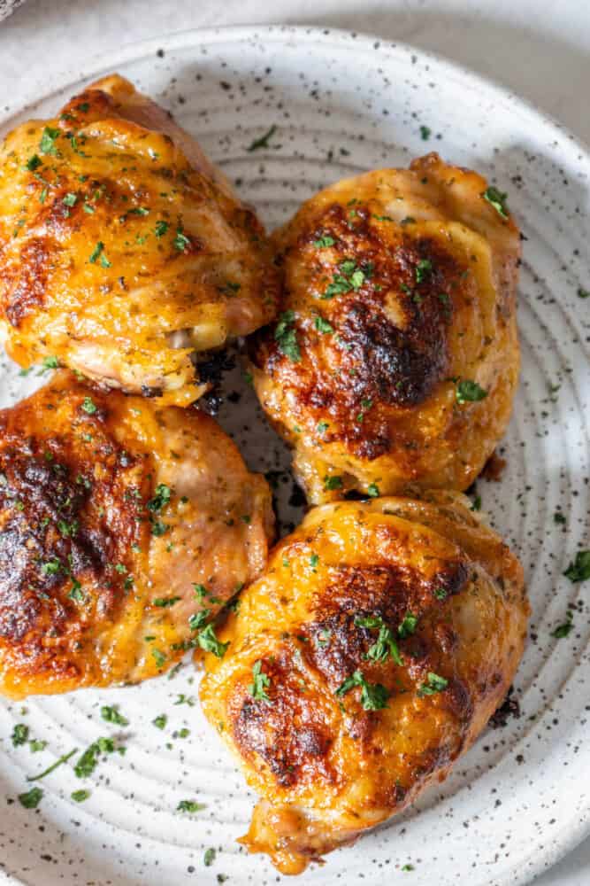 Baked ranch chicken thighs on a white plate with parsley.