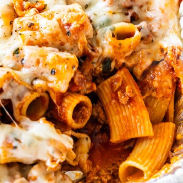 Cheesy baked rigatoni pasta with savory tomato sauce, melted cheese, and ground meat, shown close up.