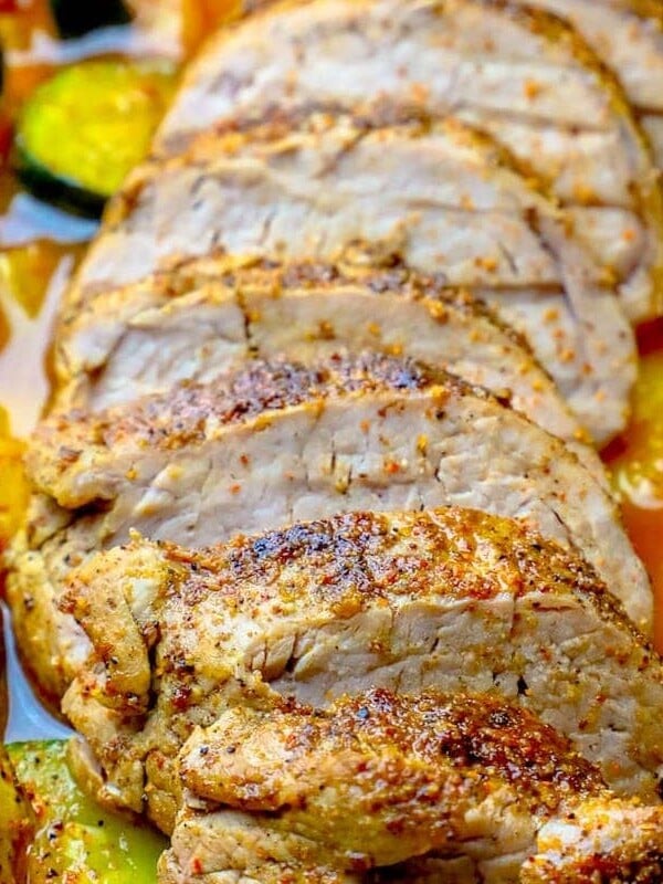 Roasted vegetables accompanies the pork tenderloin in a sheet pan.