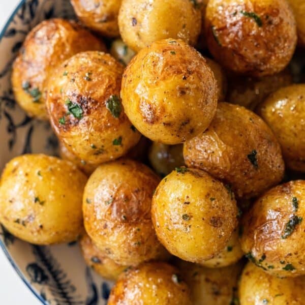 A bowl filled with golden-brown butter poached potatoes, seasoned with herbs and spices.