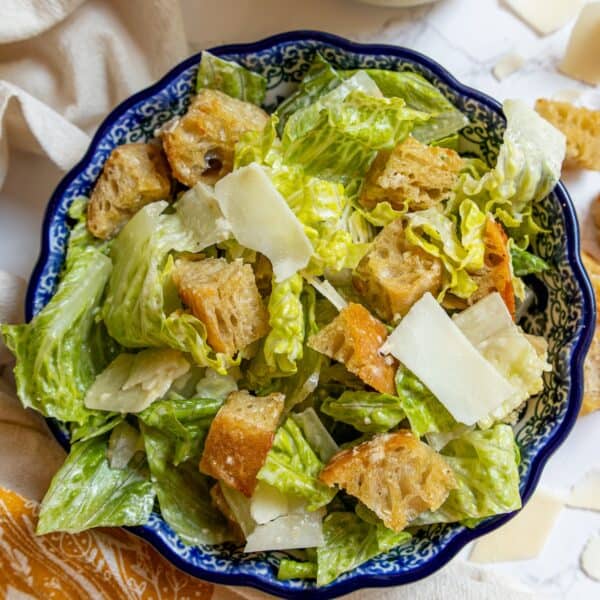 A bowl of Caesar salad with romaine lettuce, croutons, shaved Parmesan cheese, and classic Caesar dressing.