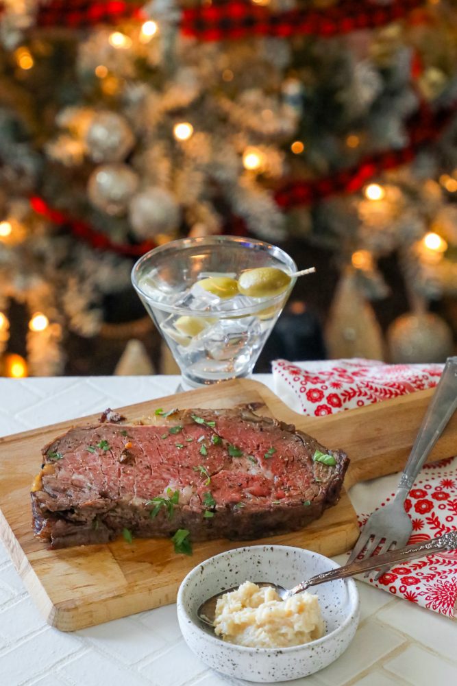 A festive presentation of a succulent steak, prepared with a garlic ribeye roast recipe, showcased on a cutting board against the backdrop of a Christmas tree.