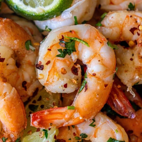 Close-up of Cilantro Lime Sautรฉed Shrimp garnished with chopped herbs, red pepper flakes, and lime wedgesโperfect for those wanting to learn how to cook shrimp with a fresh, zesty twist.