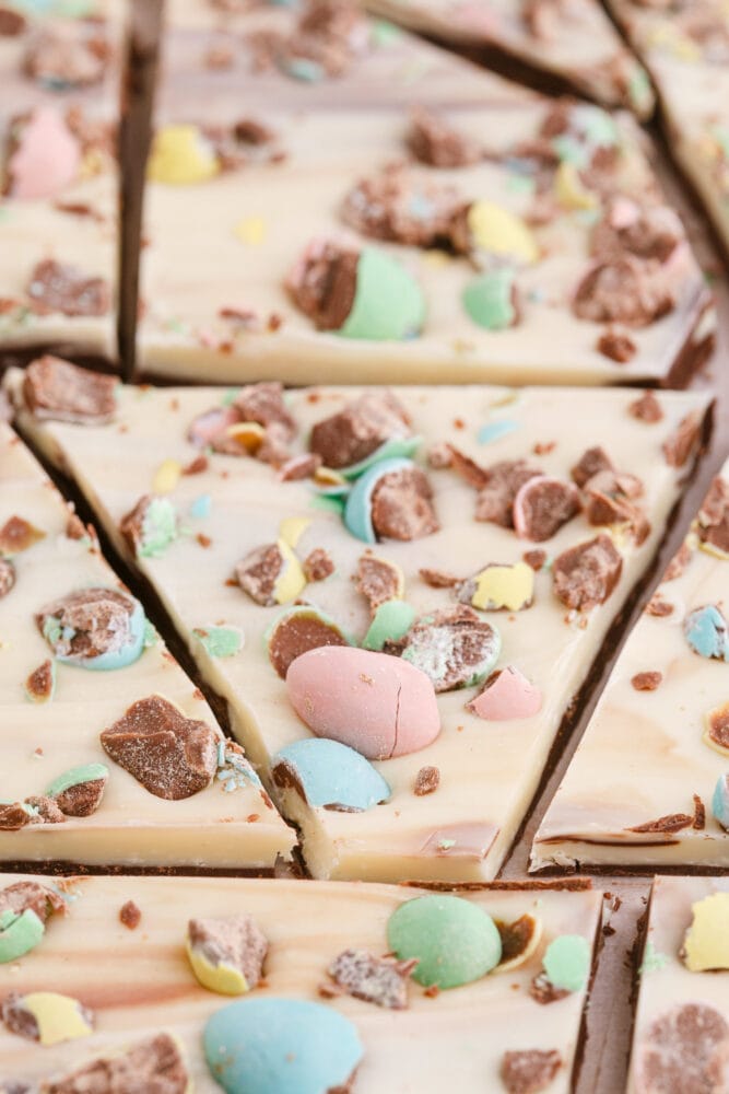 picture of white chocolate and chocolate layered easter bark with cadbury mini eggs on a wood cutting board