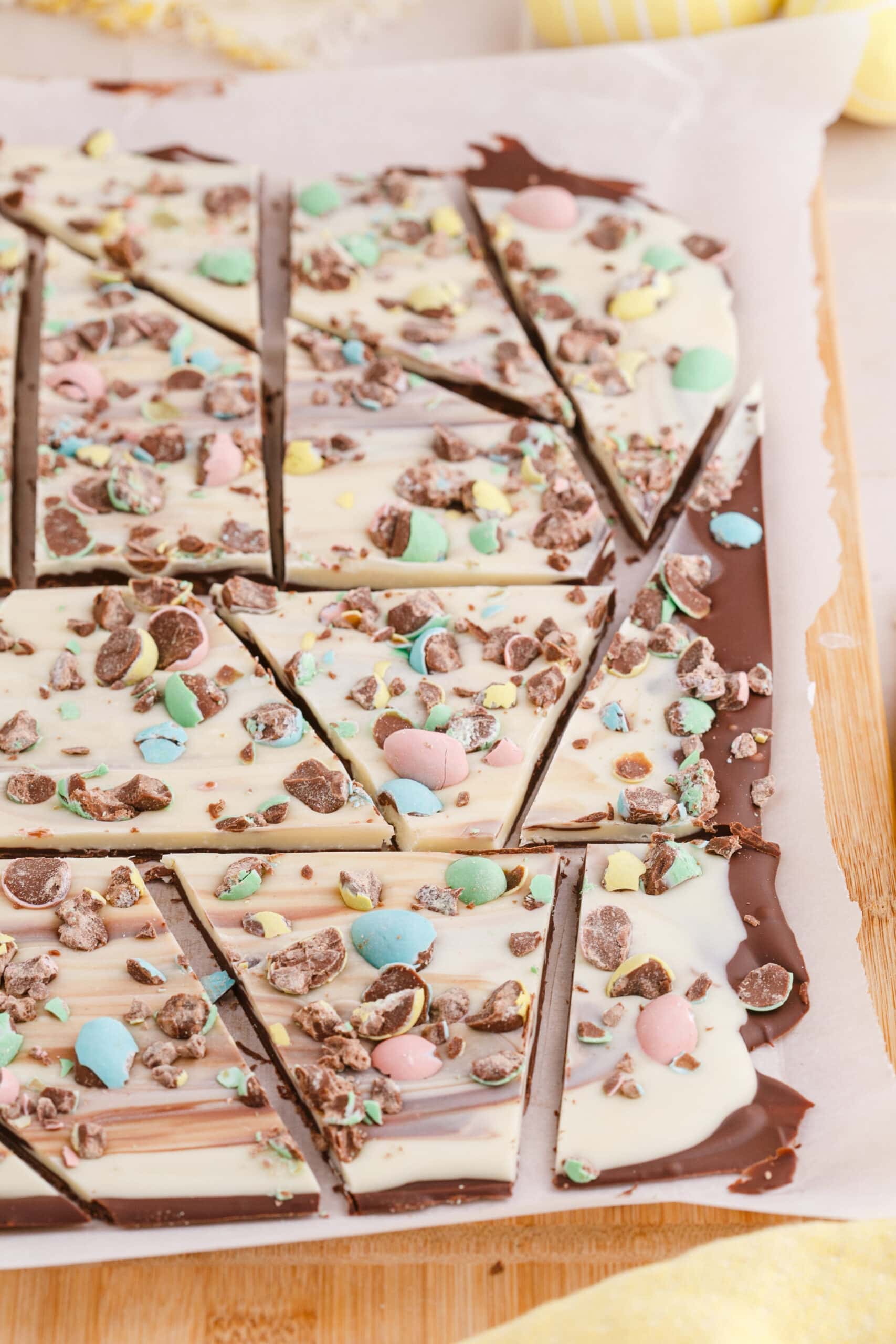 picture of white chocolate and chocolate layered easter bark with cadbury mini eggs on a wood cutting board