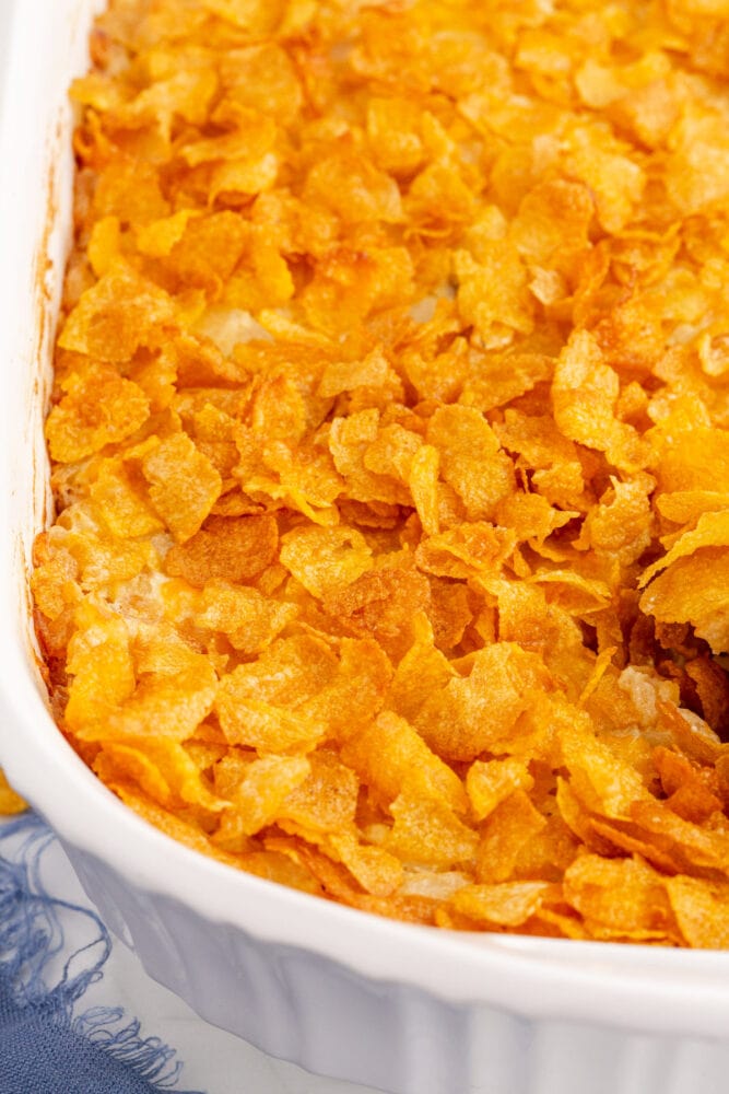 A cheesy hashbrown casserole served in a white casserole dish.