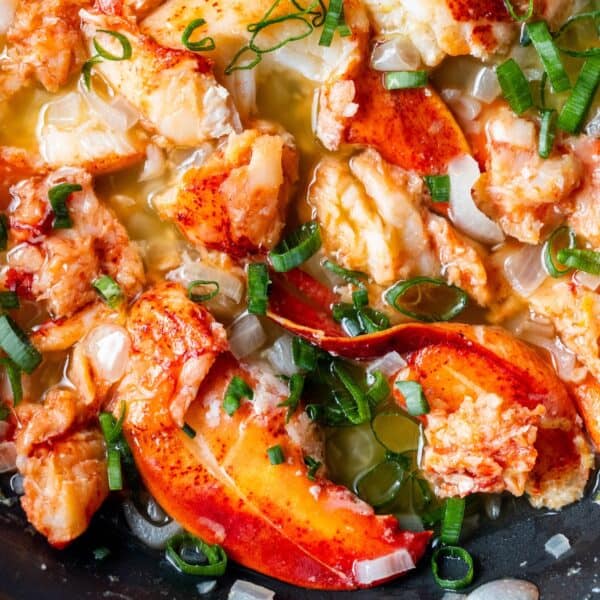 Chunks of cooked lobster meat in a buttery sauce, garnished with chopped green onionsโa perfect Easy Garlic Butter Lobster Skillet for any occasion.