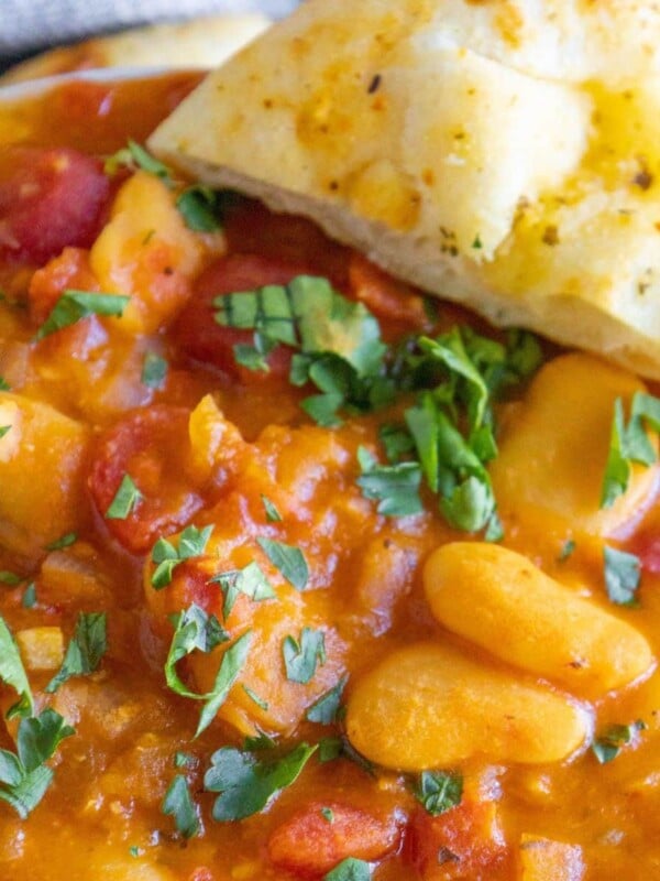 baked greek beans in a tomato sauce with chopped herbs and giant white beans