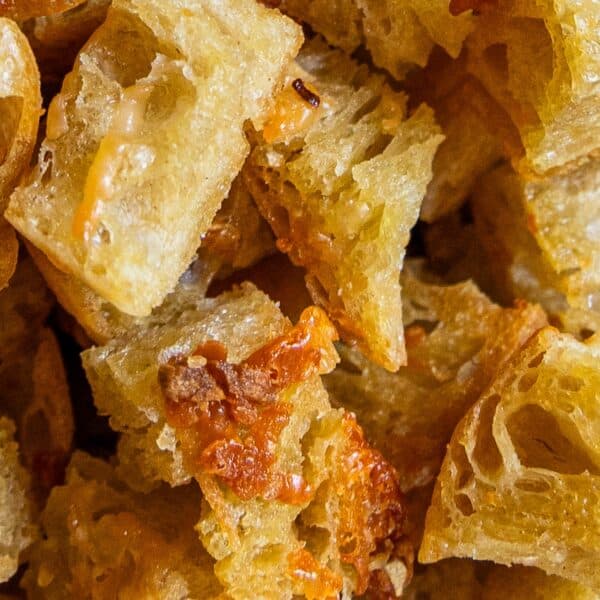 Close-up view of several pieces of bread with melted cheese, showing a crispy, golden-brown texture—perfect for making homemade croutons.