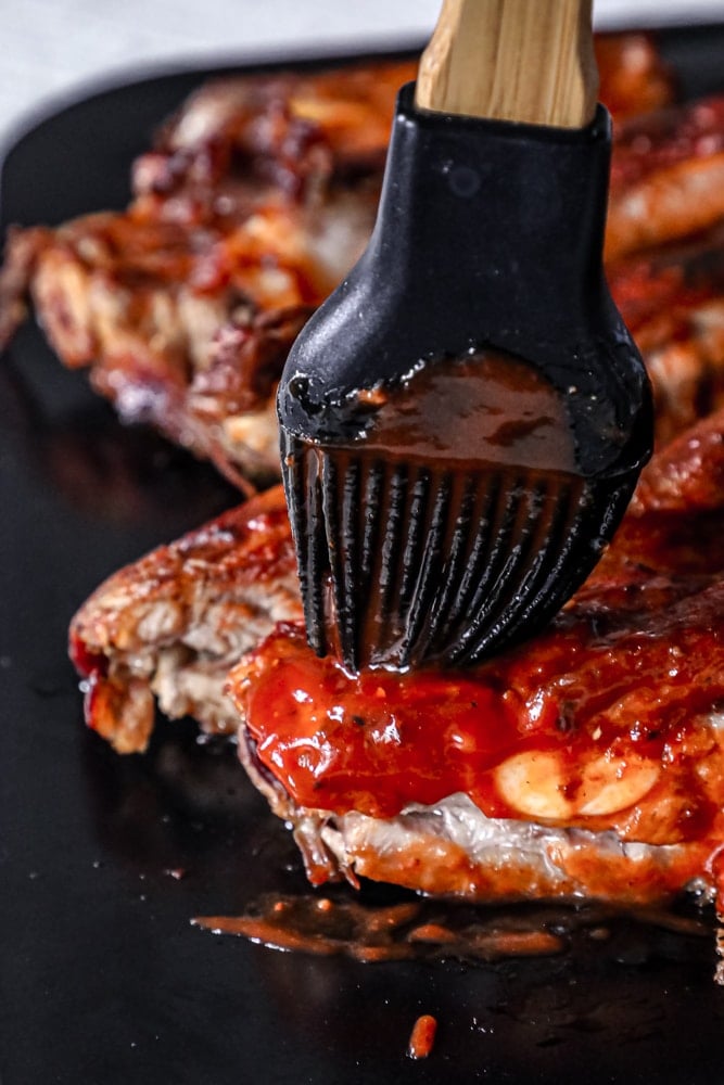 Bbq ribs being dipped in bbq sauce using a slow cooker.