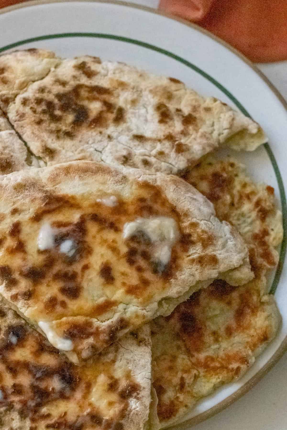 Close-up of several pieces of Irish potato bread, with browned, flaky surfaces on a white plate.