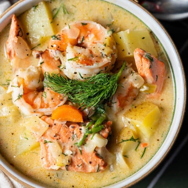 A bowl of creamy Irish Seafood Chowder with shrimp, salmon, potatoes, carrots, herbs, and a sprig of fresh dill on top.