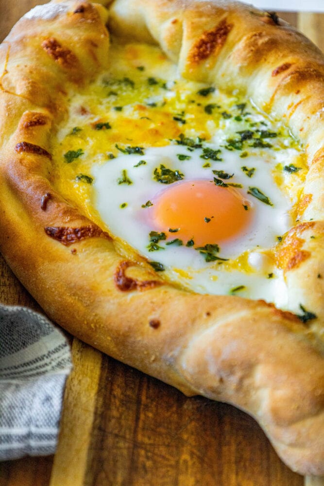 A pizza with a unique twist featuring an egg on top, inspired by the khachapuri cheese bread recipe.