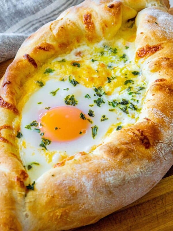 picture of baked khachapuri on a cutting board with egg on top