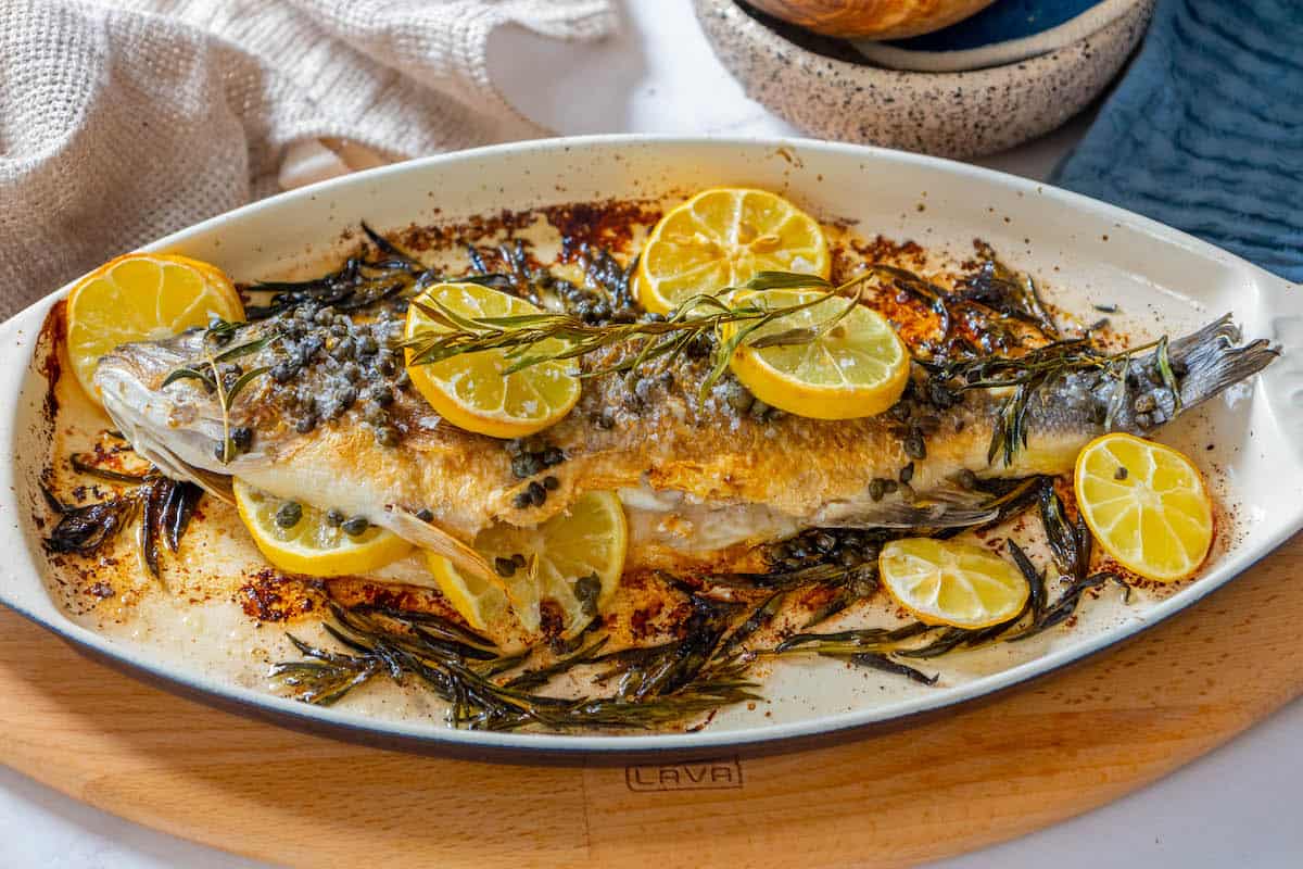 A roasted Branzino with lemon slices.
