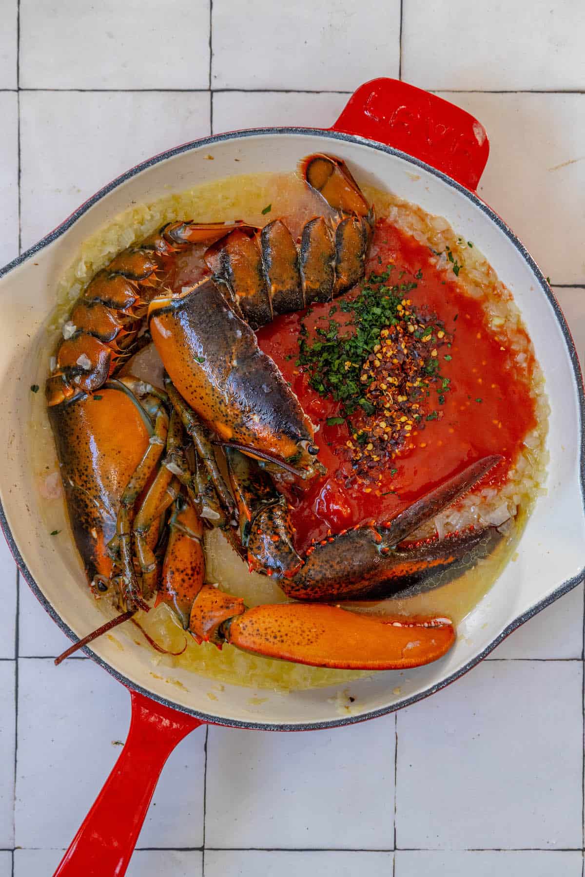 Lobster in a red skillet with tomato sauce, inspired by Venice's Busara Pasta.