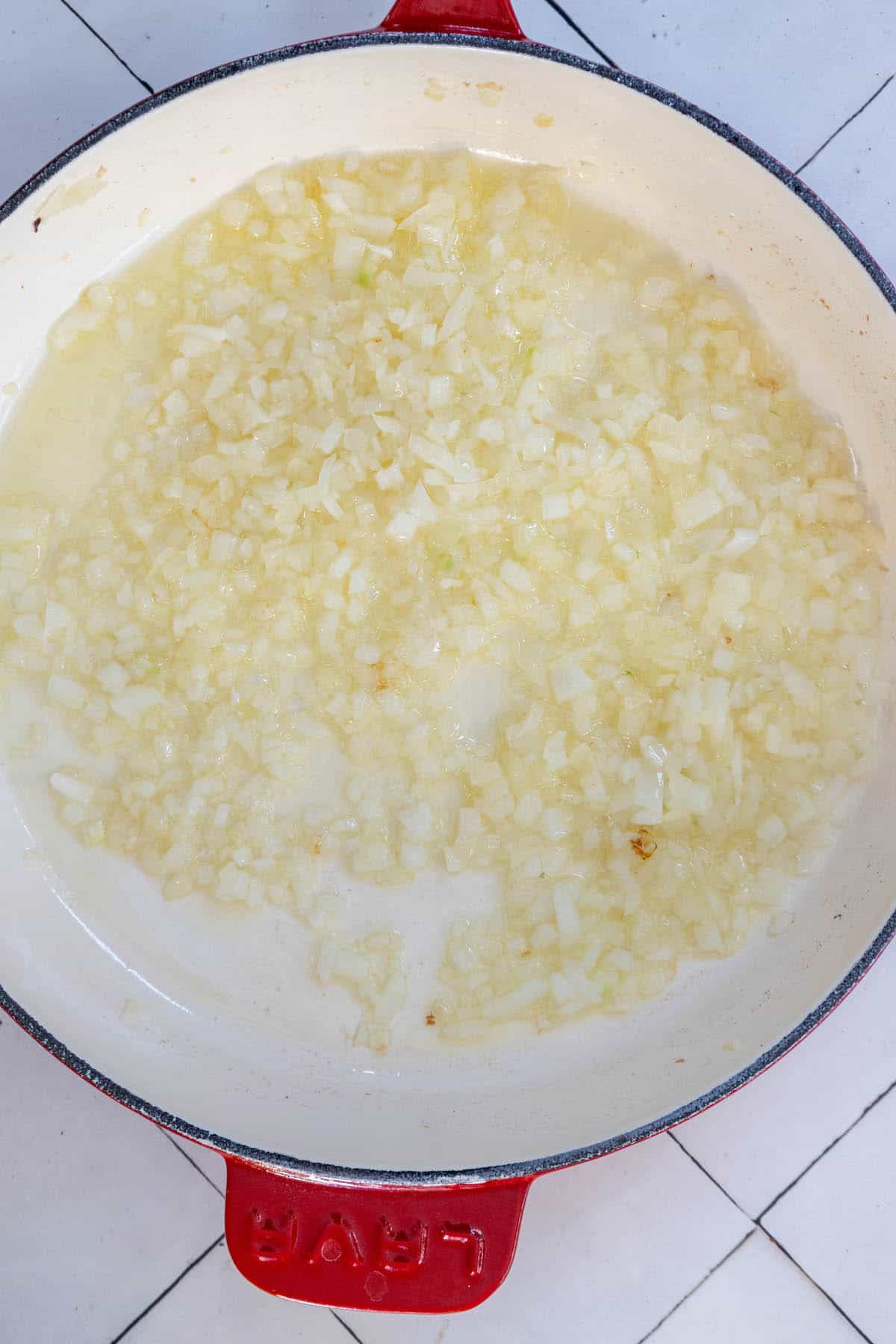 A red and white skillet on a tiled floor, showcasing the delicious Lobster Pasta Busara.