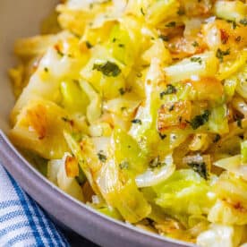 A bowl of sauteed cabbage with onions in a blue and white checkered cloth.