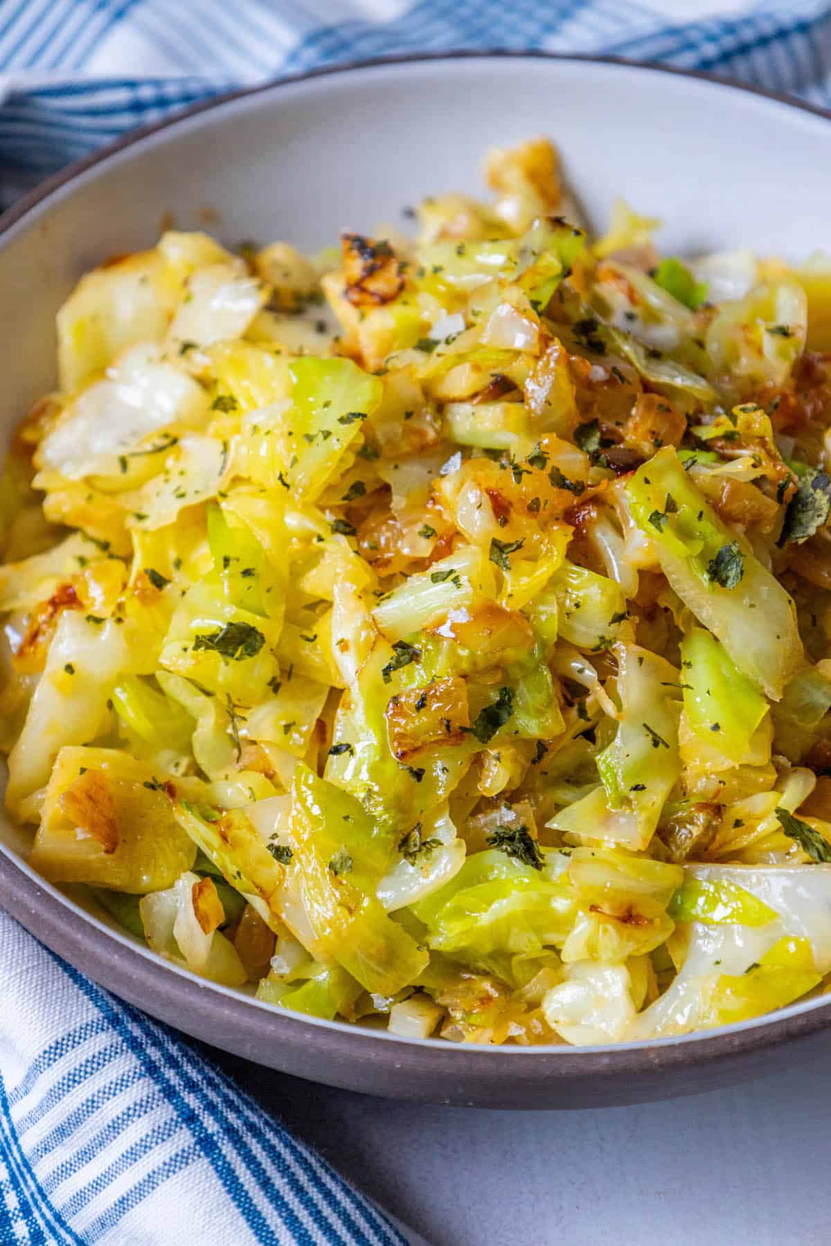 A bowl of sauteed cabbage and onions on a blue and white cloth.