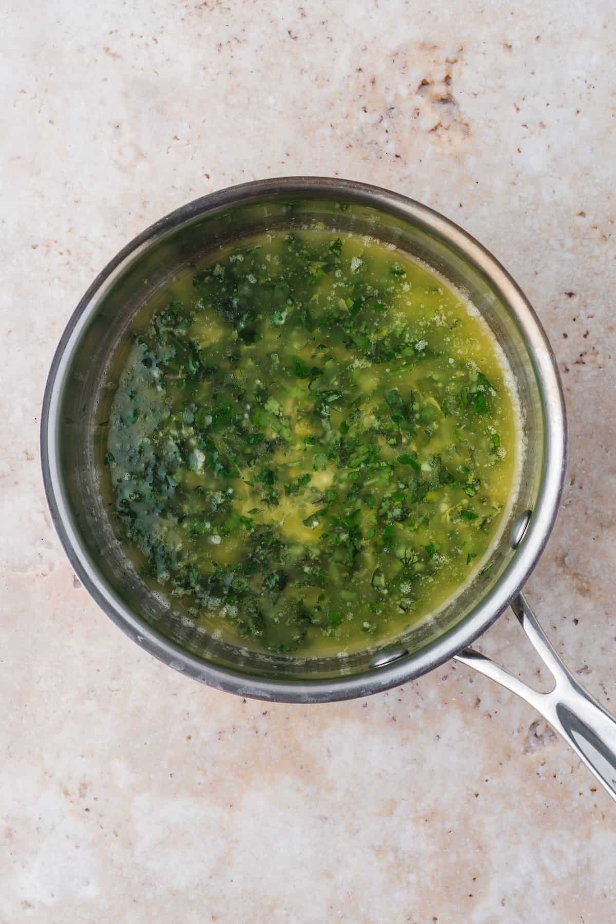 A pan with Pan Fried cod in a green sauce.
