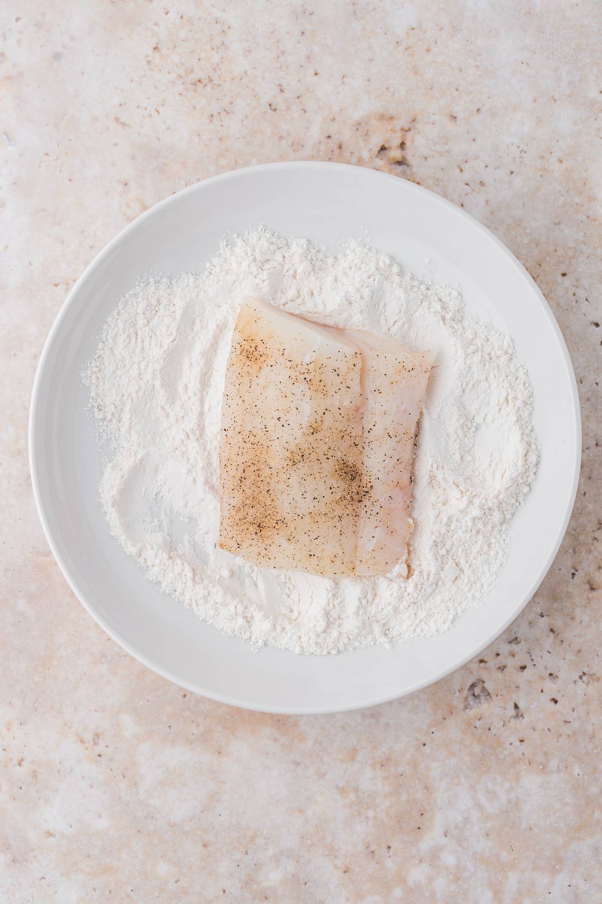 A piece of fish pan-fried with flour on a plate.
