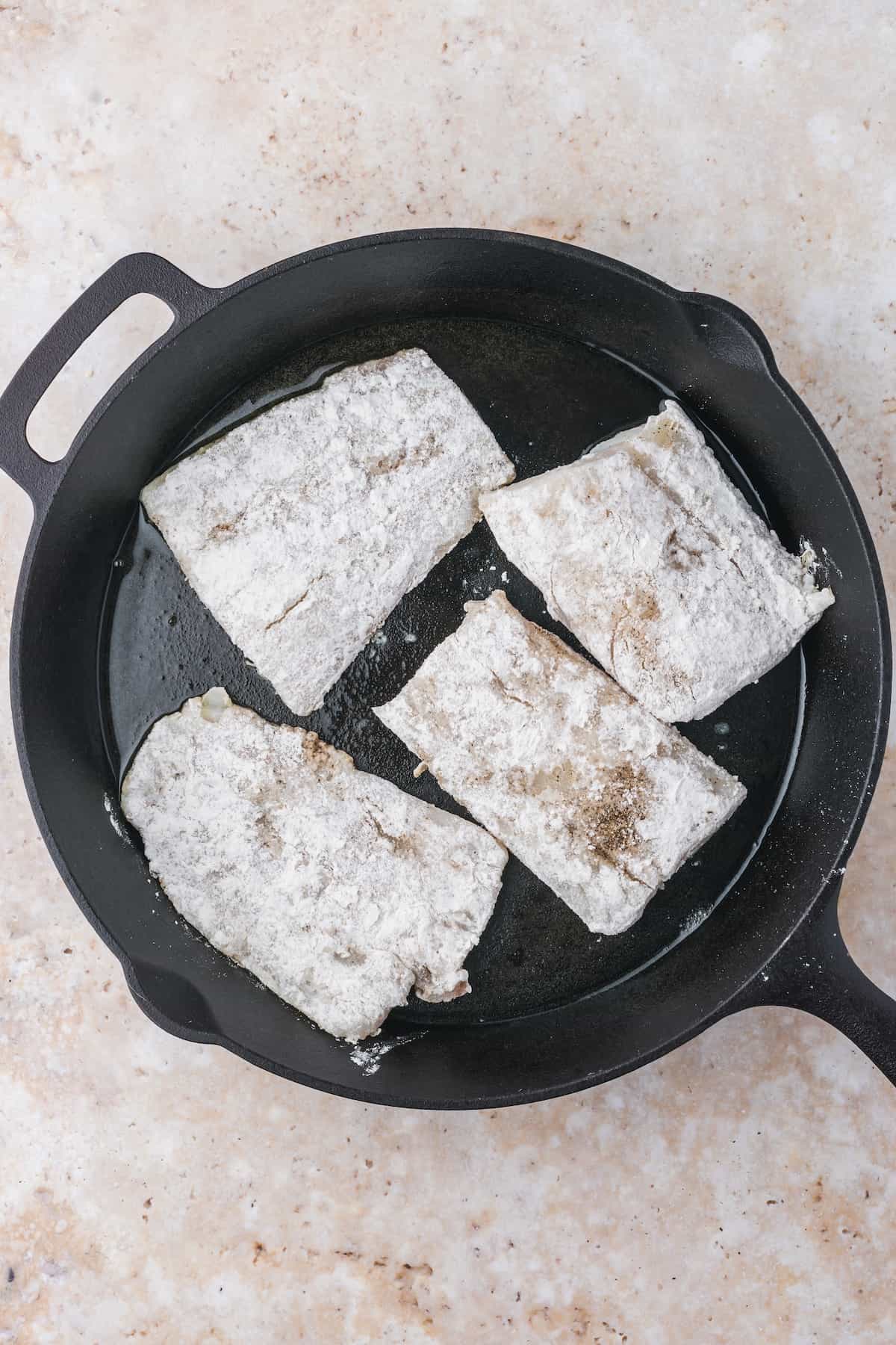 Pan seared cod fillets in a cast iron skillet.