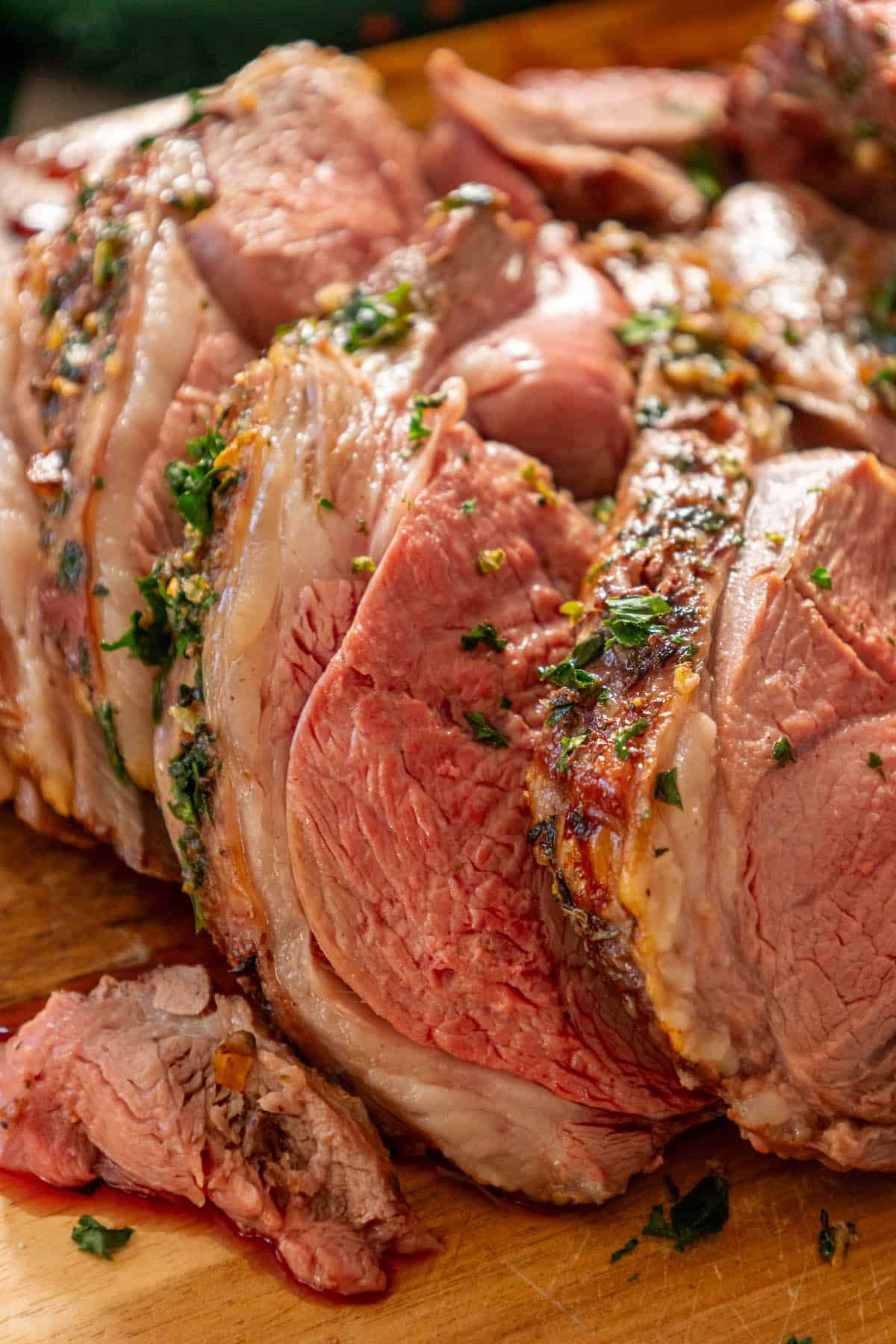 A juicy Leg of Lamb delicately placed on a wooden cutting board.