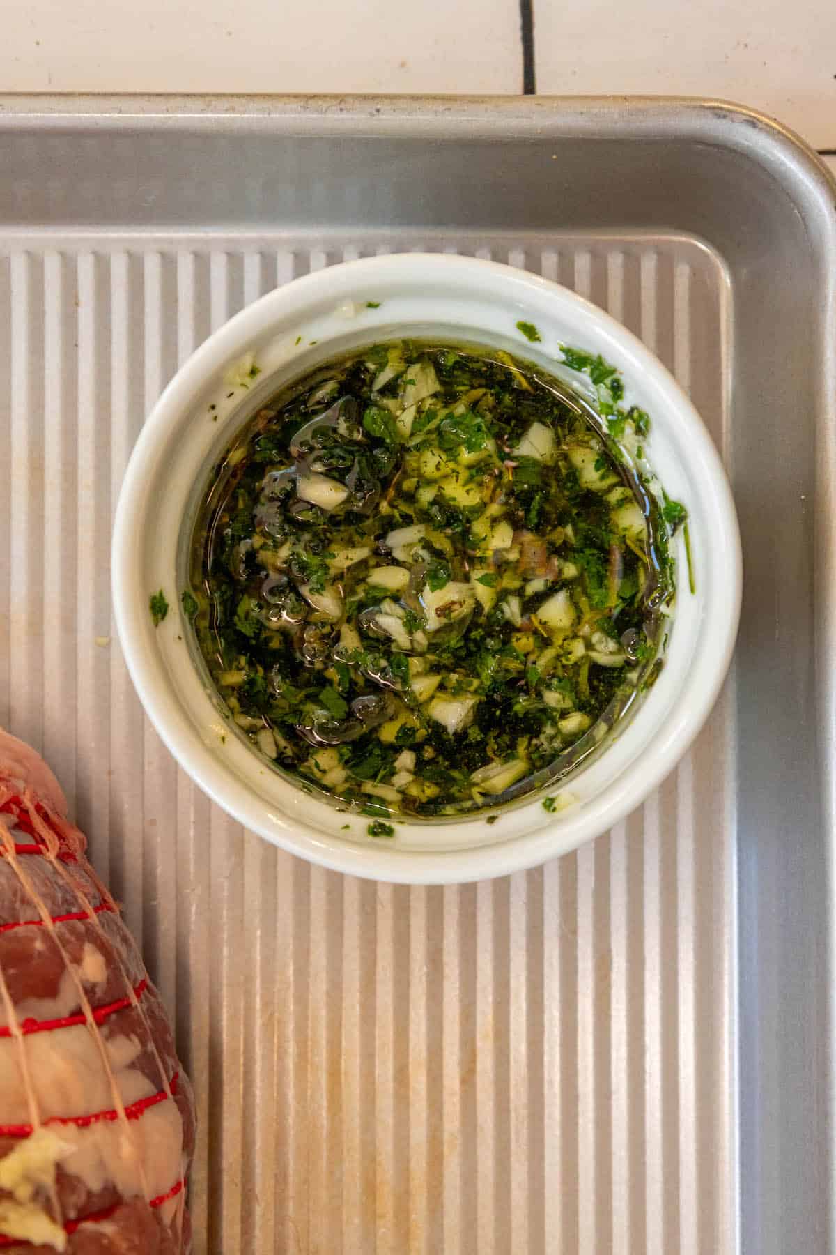 A Reverse Seared leg of lamb with herbs on a baking sheet.