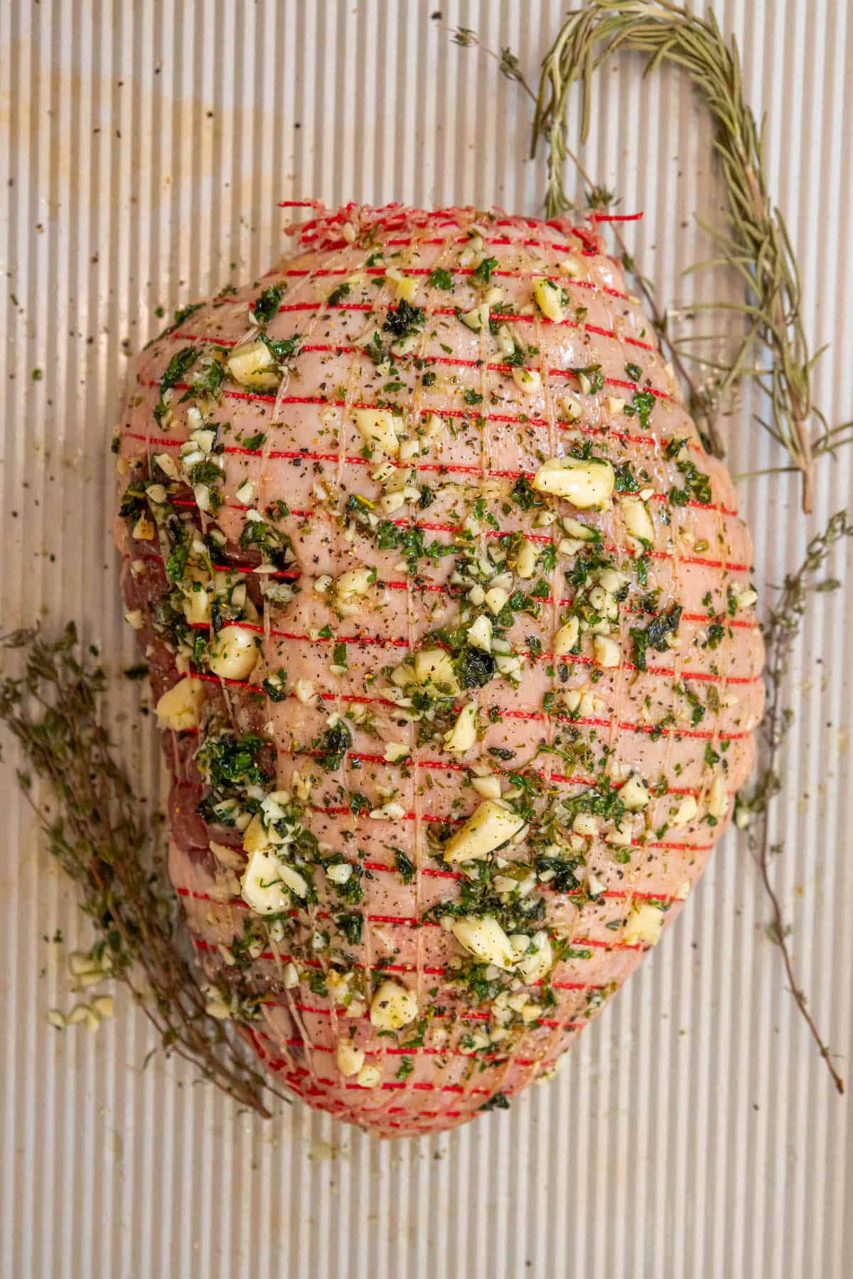 A reverse seared leg of lamb with herbs and spices on a baking sheet.