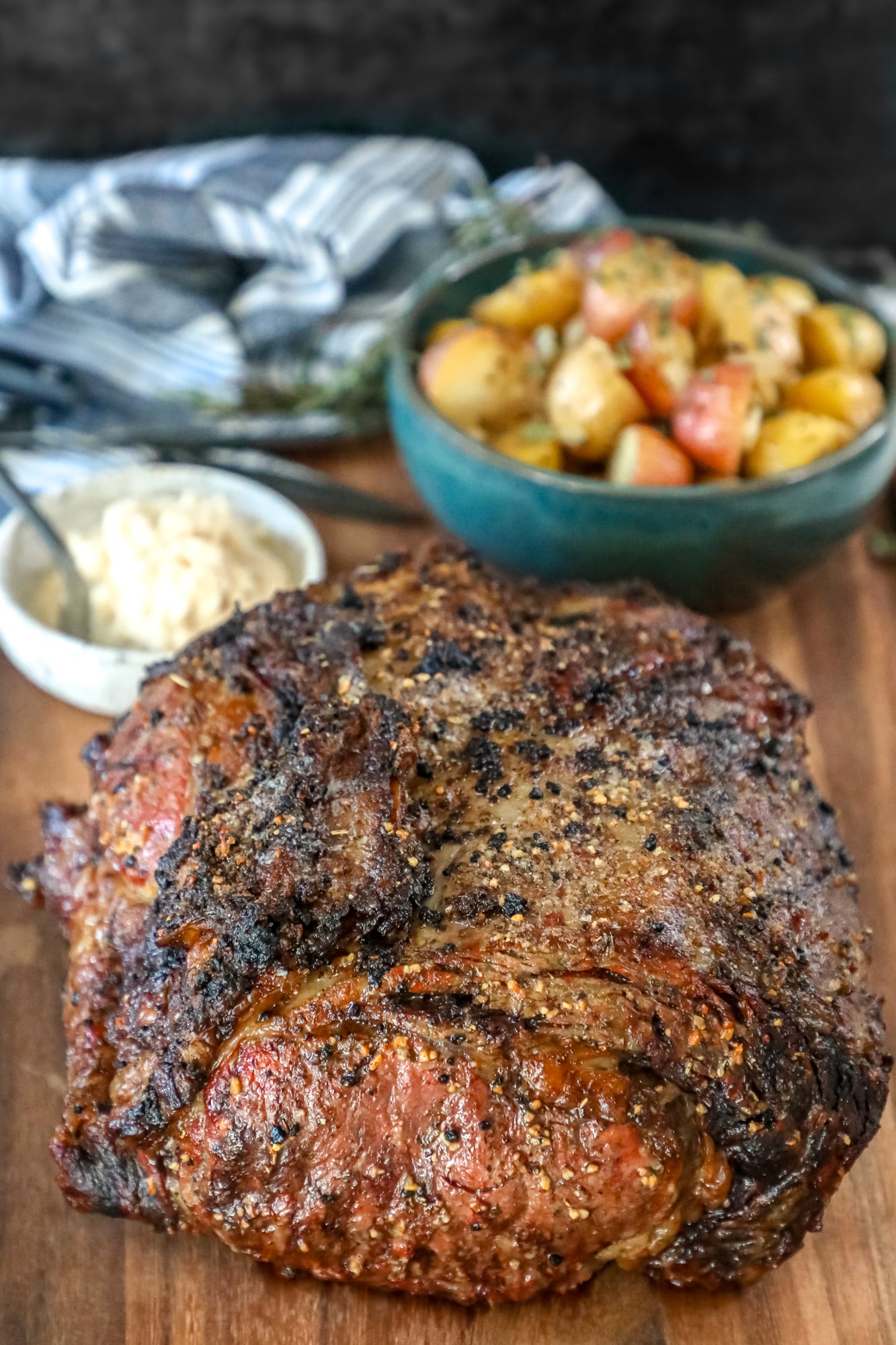 The Best Ribeye Roast Recipe with potatoes served on a cutting board.