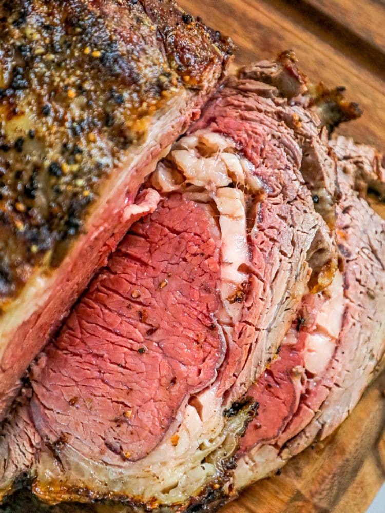 The Best Ribeye Roast Recipe Story: A succulent sliced roast on a wooden cutting board.