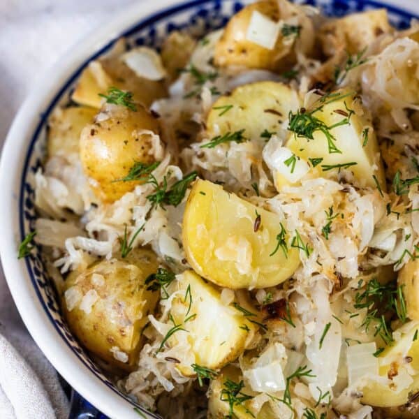 A bowl of roasted potatoes tossed with tangy sauerkraut, chopped onions, and fresh dill.