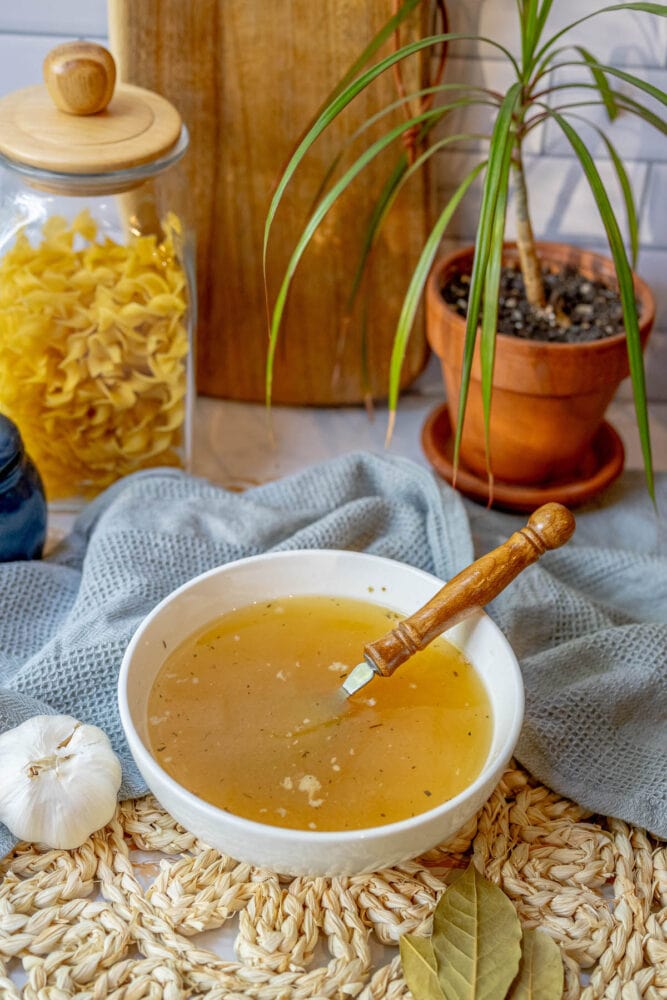 A slow-cooked bowl of turkey soup with a wooden spoon on a table.