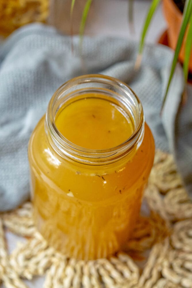 A jar of honey next to a plant, placed on a table.