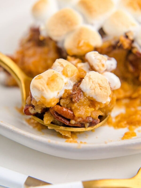 Sweet potato casserole topped with marshmallows and pecans on a plate.