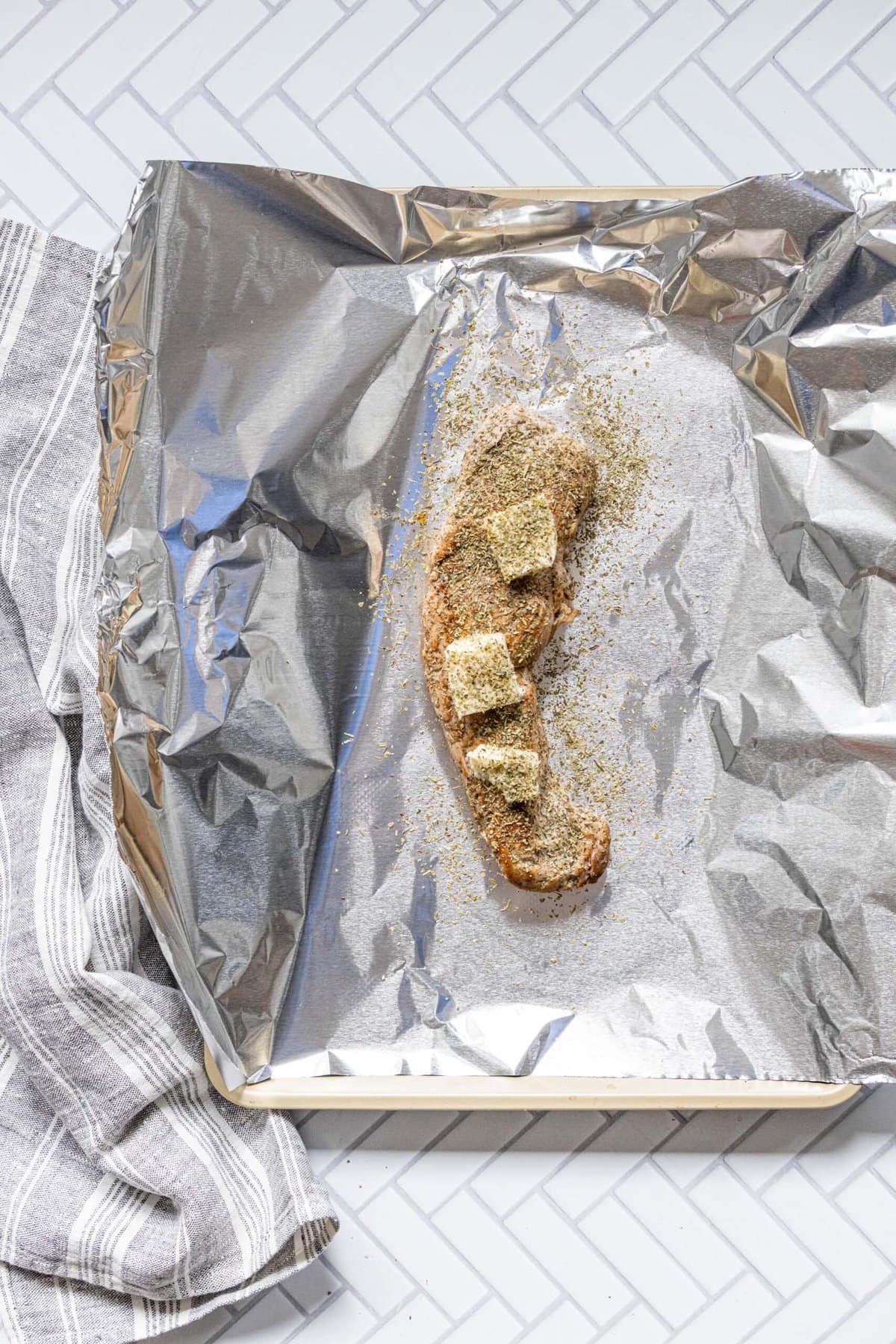 browned pork tenderloin on a piece of foil on a baking sheet