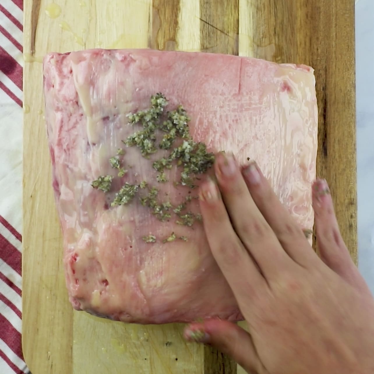hand rubbing herbs onto ribeye roast