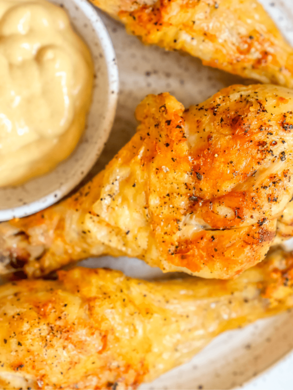 picture of air fried chicken drumsticks on a white plate with mustard dipping sauce next to it
