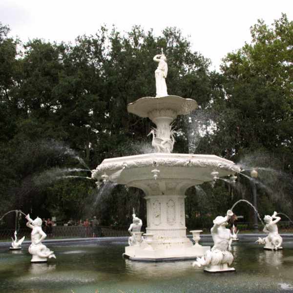 Large ornate fountain with multiple tiers and statues, water spraying from various points, surrounded by greenery and trees—a must-see highlight in any savannah travel guide.