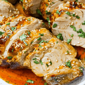 Sliced cooked chicken breast topped with chopped herbs and sesame seeds, served with a reddish sauce inspired by our baked teriyaki pork tenderloin recipe.